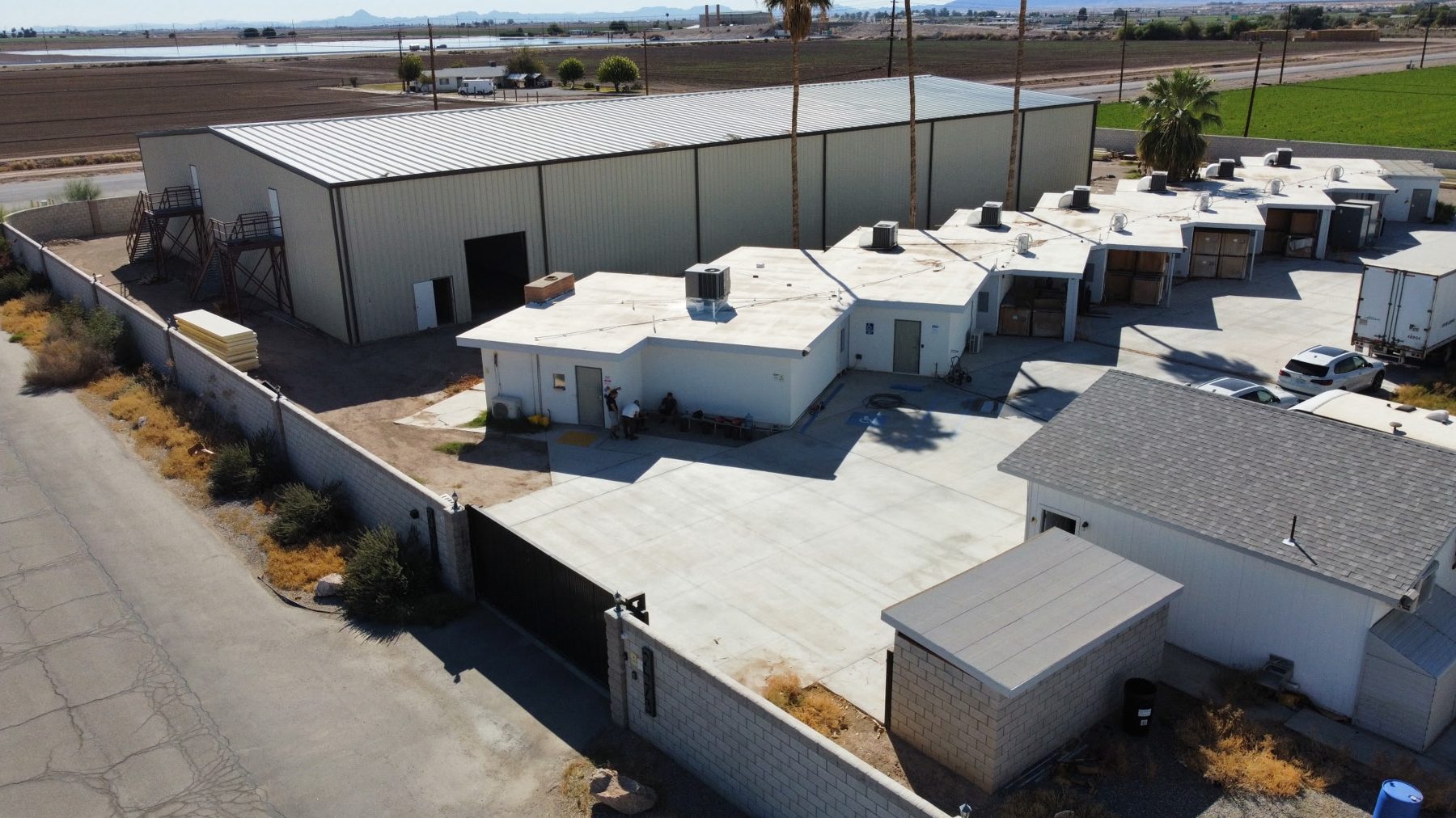 Aerial view of the walled Blythe site: large metal main building with a row of grow rooms and a paved, gated yard